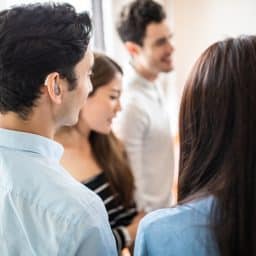 Young man with a hearing aid socializing with friends at a party.